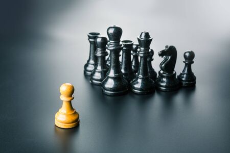 White pawn standing in front of the black chess teamの写真素材
