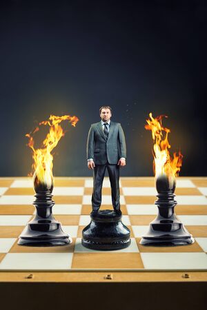 Businessman standing on the chess board instead of a pawn between two blamesの写真素材