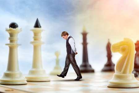 Businessman is walking on the chess board thinkingの写真素材