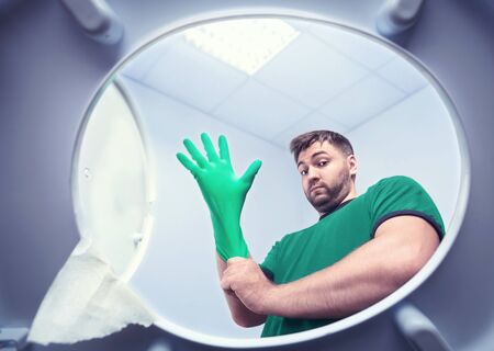 Man in the bathroom in rubber glove ready to clean the toiletの写真素材