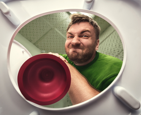 Man cleaning the toilet with cup plungerの写真素材
