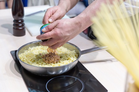 Cook cooking tuna pasta on the pan close up