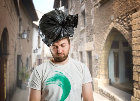 Sad man with trash pack on his head on the streetの写真素材