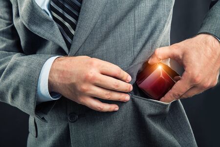 Businessman putting a gift-box in the pocket close upの写真素材