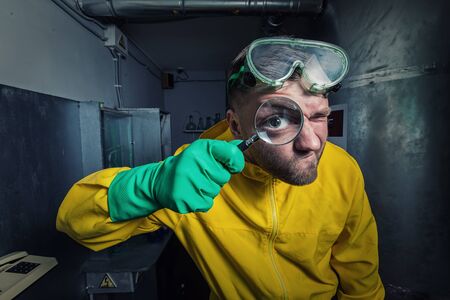 Man wearing protective outerwear suit in the lab with magnifierの写真素材