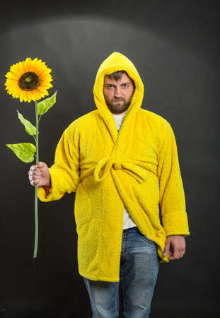 Man in yellow bathrobe holding a sunflowerの写真素材
