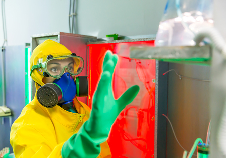 Woman wearing protective outerwear suit in chemical laboratory with flask