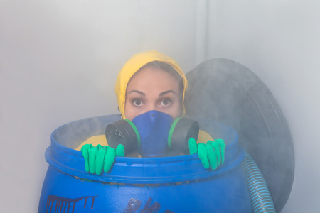 Woman in gas mask sitting in the barrelの写真素材