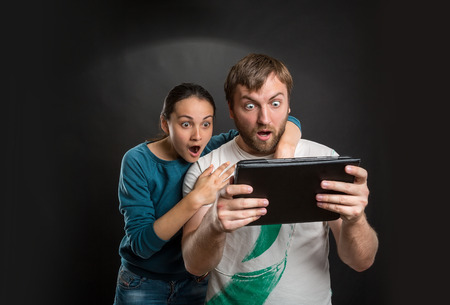 Very excited man and woman playing with tabletの写真素材