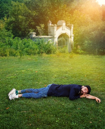 Homeless man sleeping on the green lawnの写真素材