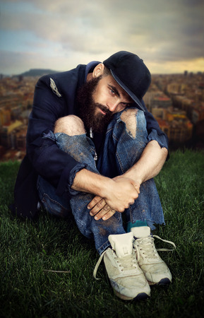 Sad vagrant sitting on the meadowの写真素材