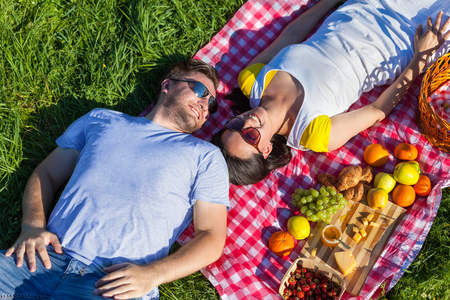 Young couple lying on the blanket during picnicの写真素材