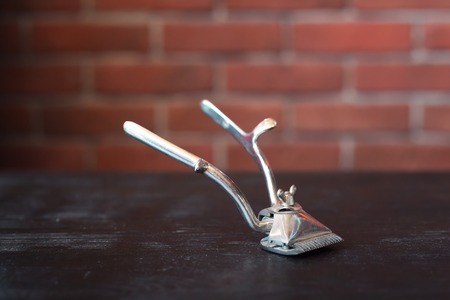 Vintage steel hair clipper on the table over brick wallの写真素材