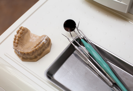 Dentist instruments and an artificial jaw on the tableの写真素材