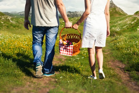 Young couple holding a basket walking in natureの写真素材