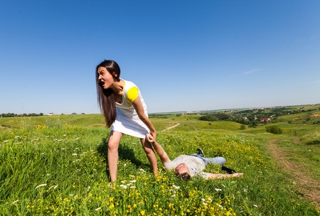 Woman pulling a slapped man after a picnic on natureの写真素材