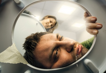 Man puking in the toilet bowl, woman is watching contemptuousの写真素材