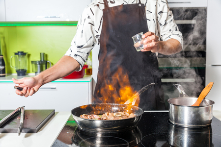 Man cooking meat at home, meat is burning in the panの写真素材