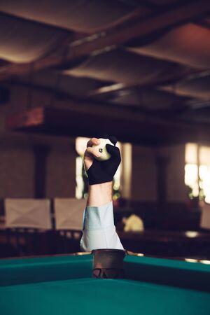 Man's hand holding billiard ball above the pocket