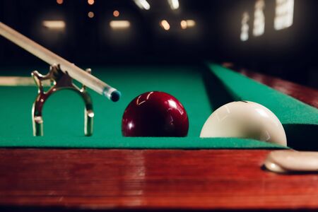 Close up of cue on the stand and billiard balls near the pocket