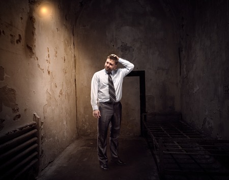Businessman standing in an old dark jailの写真素材