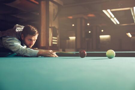 Young man concentrating while playing billiardの写真素材
