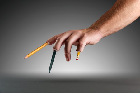 Male hand with pen and pencils instead of fingers over greyの写真素材