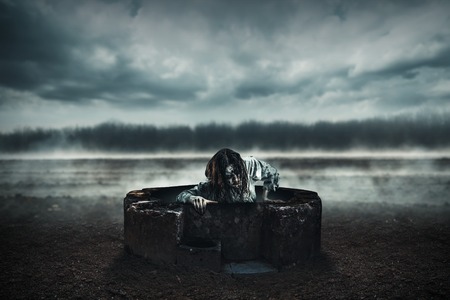 The corpse woman gets out of a well against the background of the soaring earth.  Halloween.の写真素材