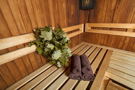 Sauna for relaxation and spa therapy, towel on the wooden bench and broom on the background.の写真素材