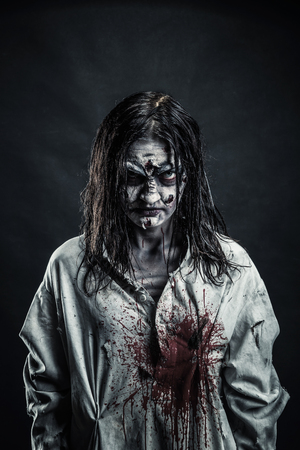 Portrait of the horror zombie woman with bloody face against the black backgroundの写真素材