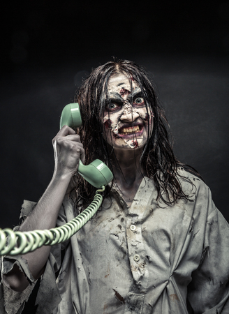 Portrait of the horror zombie girl calling by telephone. Scaryの写真素材