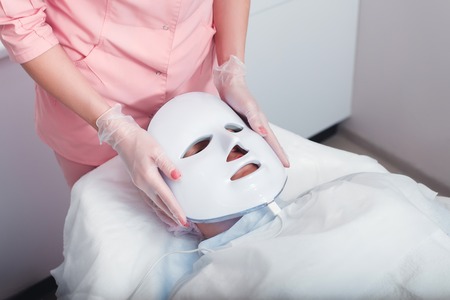 Woman in the light photodynamic mask lying on a couch in a beauty salon. Pdt.の写真素材