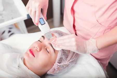 Doctor with ultrasound scraber doing procedure of ultrasound cleaning of face. Cosmetological...