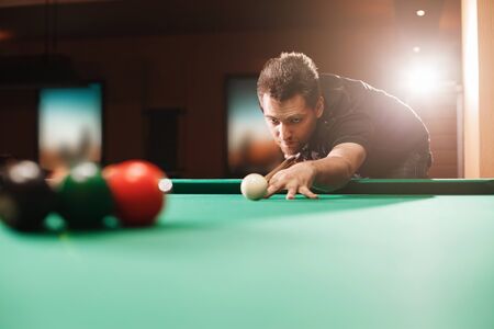 Player breaks a pyramid in billiards. Nightlife. Billiard room on the background.