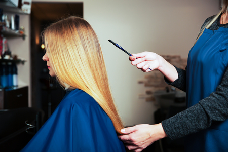 Professional hairdresser with brush in hand behind young female in hairdressing salon.の写真素材