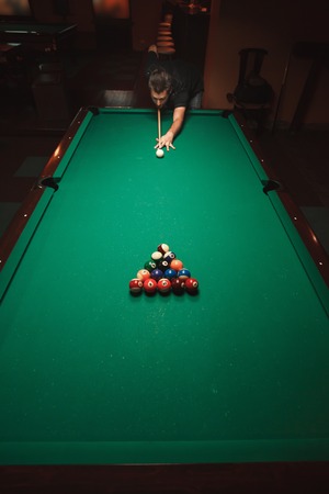 Player prepares to breaks a pyramid in billiards. Nightlife. Billiard room on the background. Above view.の写真素材