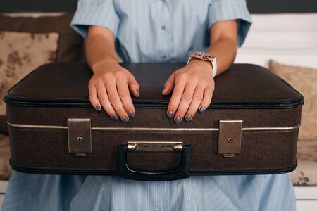 Female hands  putting on luggage. Woman sitting on couch and waiting for a trip.の写真素材