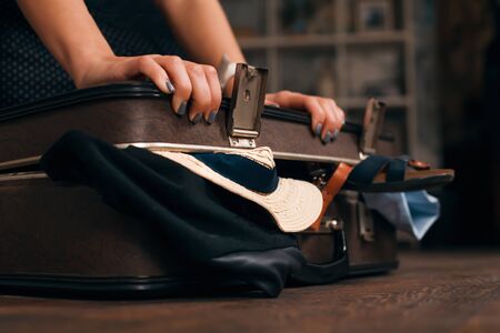 Woman having problem with closing a suitcase. Travel concept.