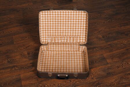 Top view of empty open retro suitcase on the wooden floor. Travel concept.の写真素材