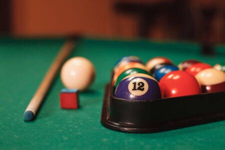 Billiard balls in triangle near by cue and chalk on the pool table.