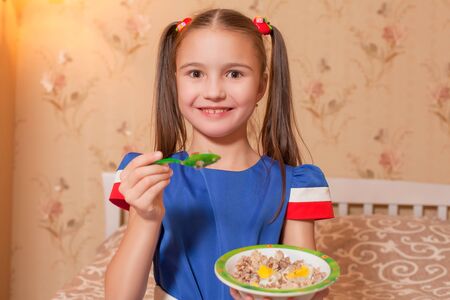 Smiling little girl with plate and spoon in hands.の写真素材