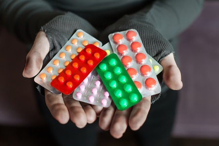 Male hands is holding a lot of different tablets. Health problem concept.の写真素材