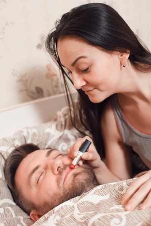 Woman makes up the mans lips with lipstickの写真素材