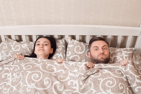 Top view of young couple showing surprise in bed.の写真素材