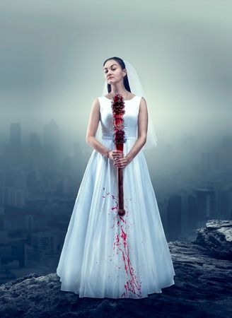 Bride in white wedding dress with bloody batの写真素材