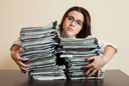 Tired accountant hugs big stacks of documentsの写真素材