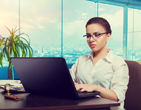 Female bookkeeper in glasses using laptopの写真素材