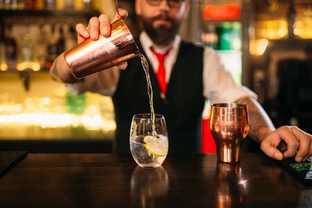 Bartender is making alcohol cocktail at counterの写真素材