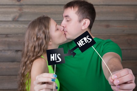 Couple kisses and shows funny icons on a sticksの写真素材
