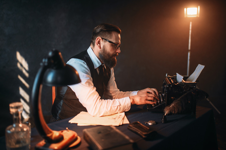 Literature author in glasses typing on typewriterの写真素材